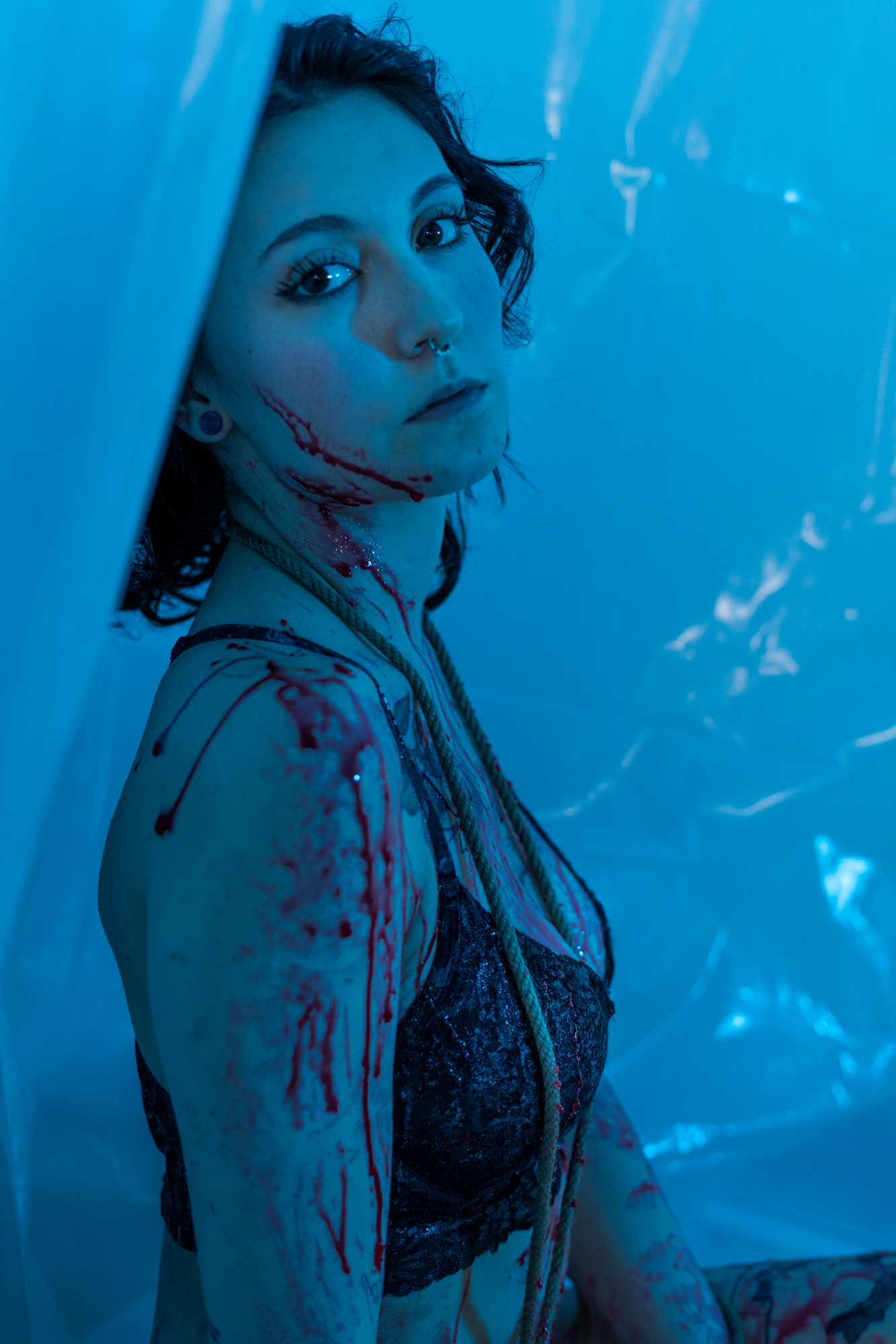 Best boudoir shot: Beautiful woman in lingerie against a high-contrast, blue-lit background, adorned with faux blood and draped in artistic rope.