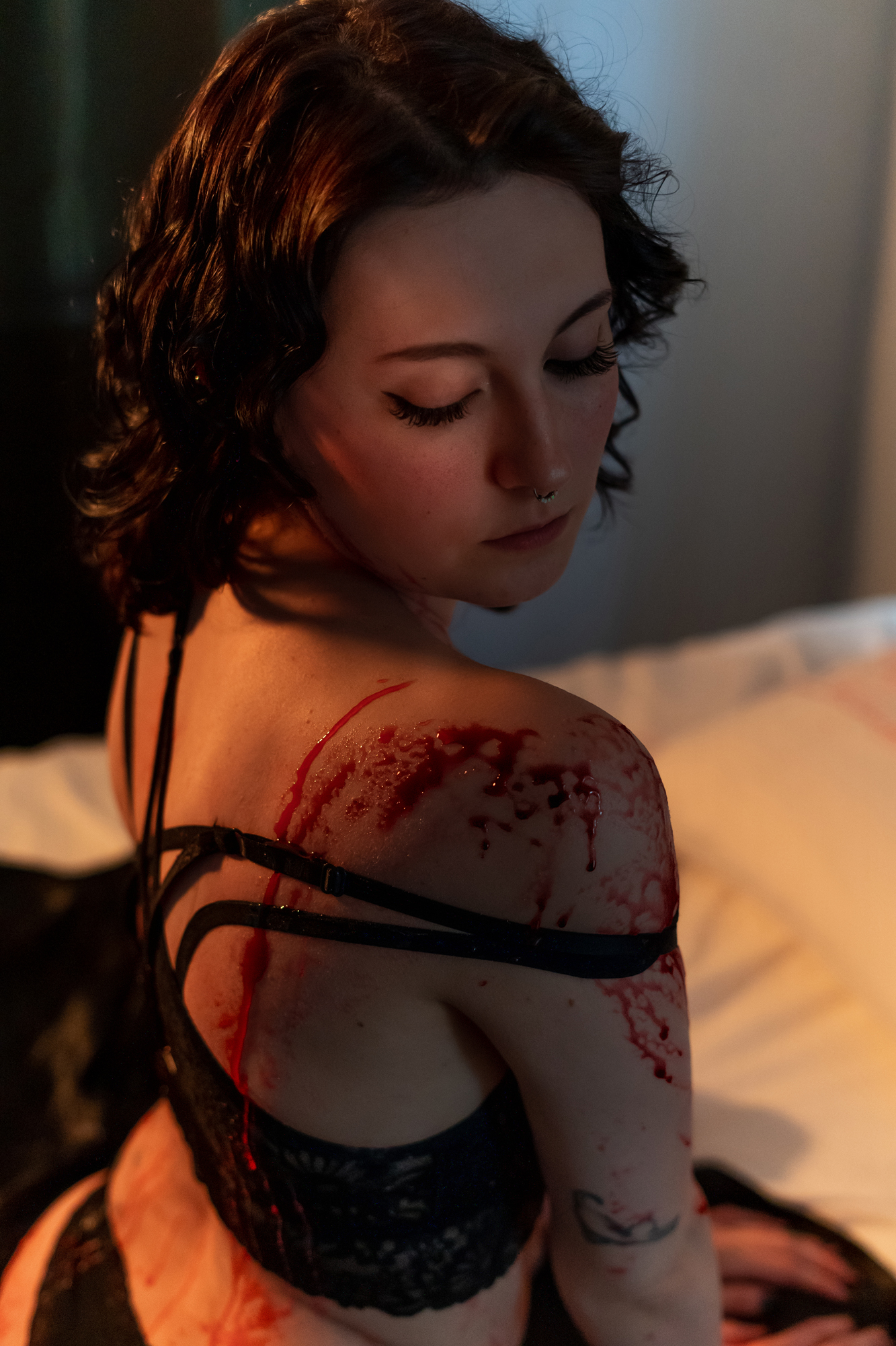 Best boudoir shot: Beautiful woman in lingerie, turning head with faux blood on her shoulder, evoking an alluring and artistic scene.